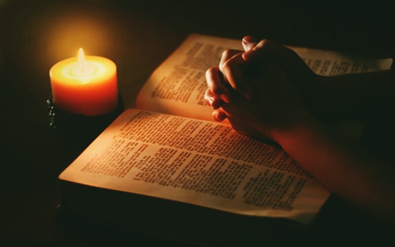 Hands Praying over Book