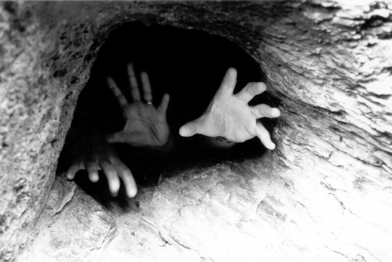 hands reaching from a cave