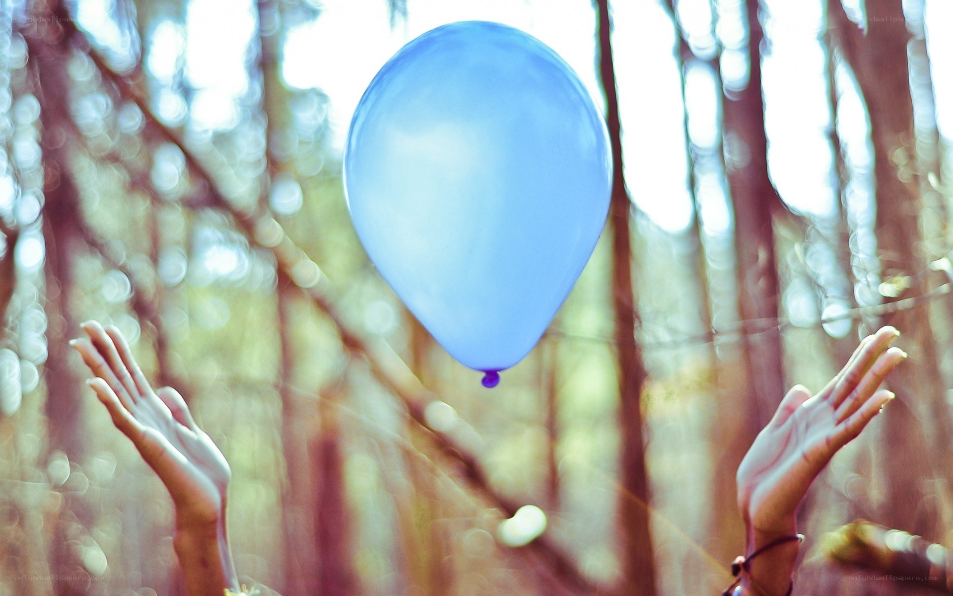 hands releasing a blue balloon