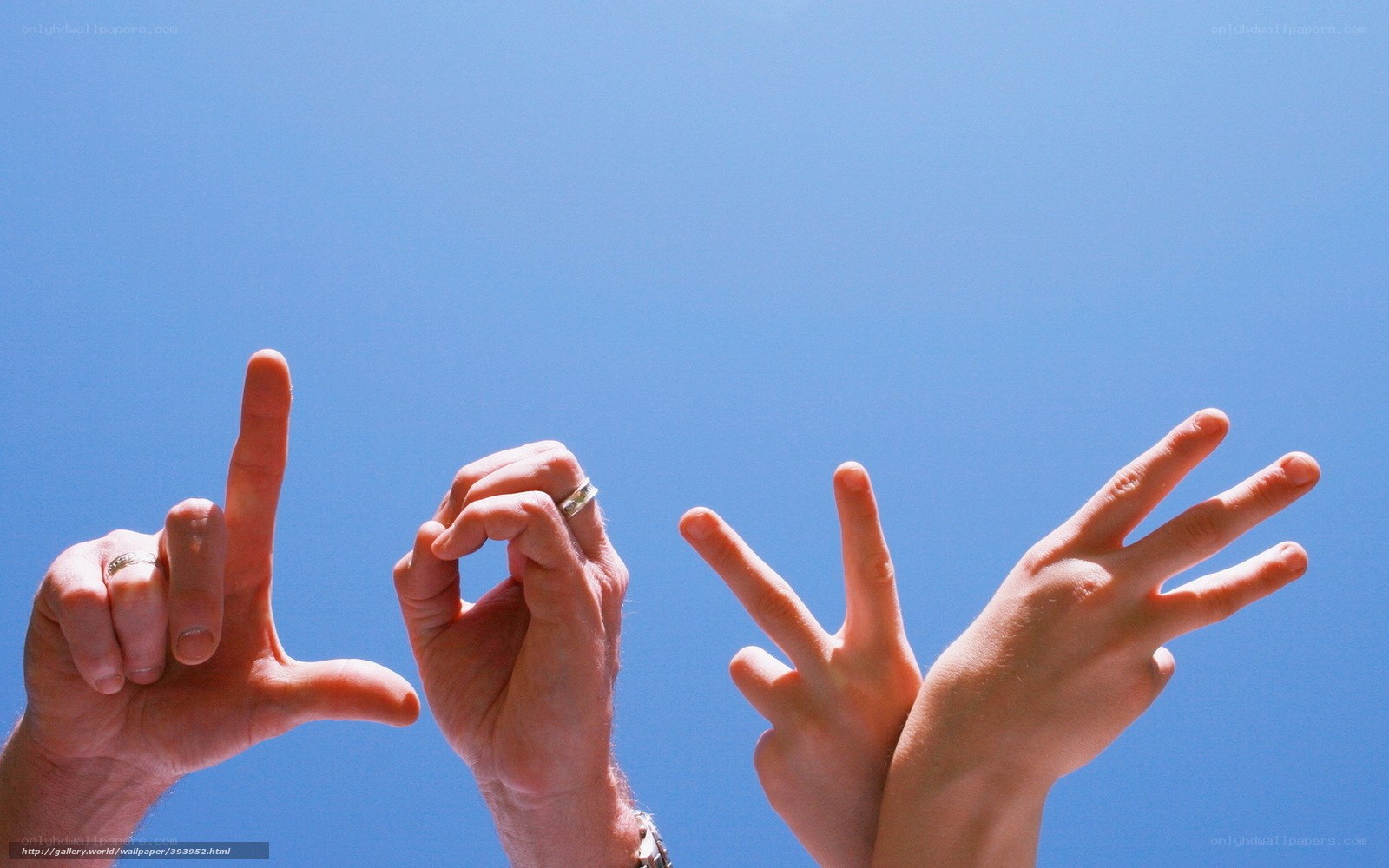 hands spelling love against blue sky