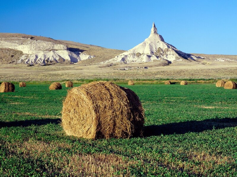 Hay bales in a field with a rock formation