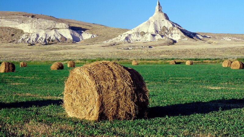 Hay bales in a field with rock formation