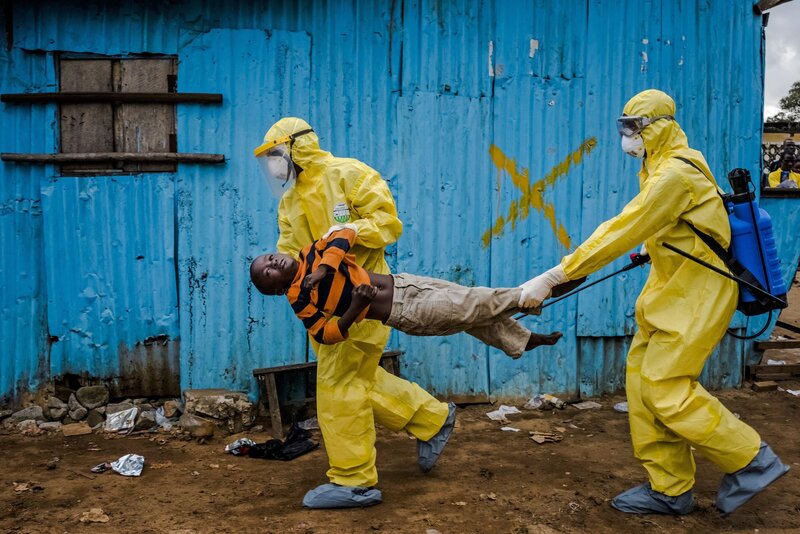 Health workers carry child in protective gear