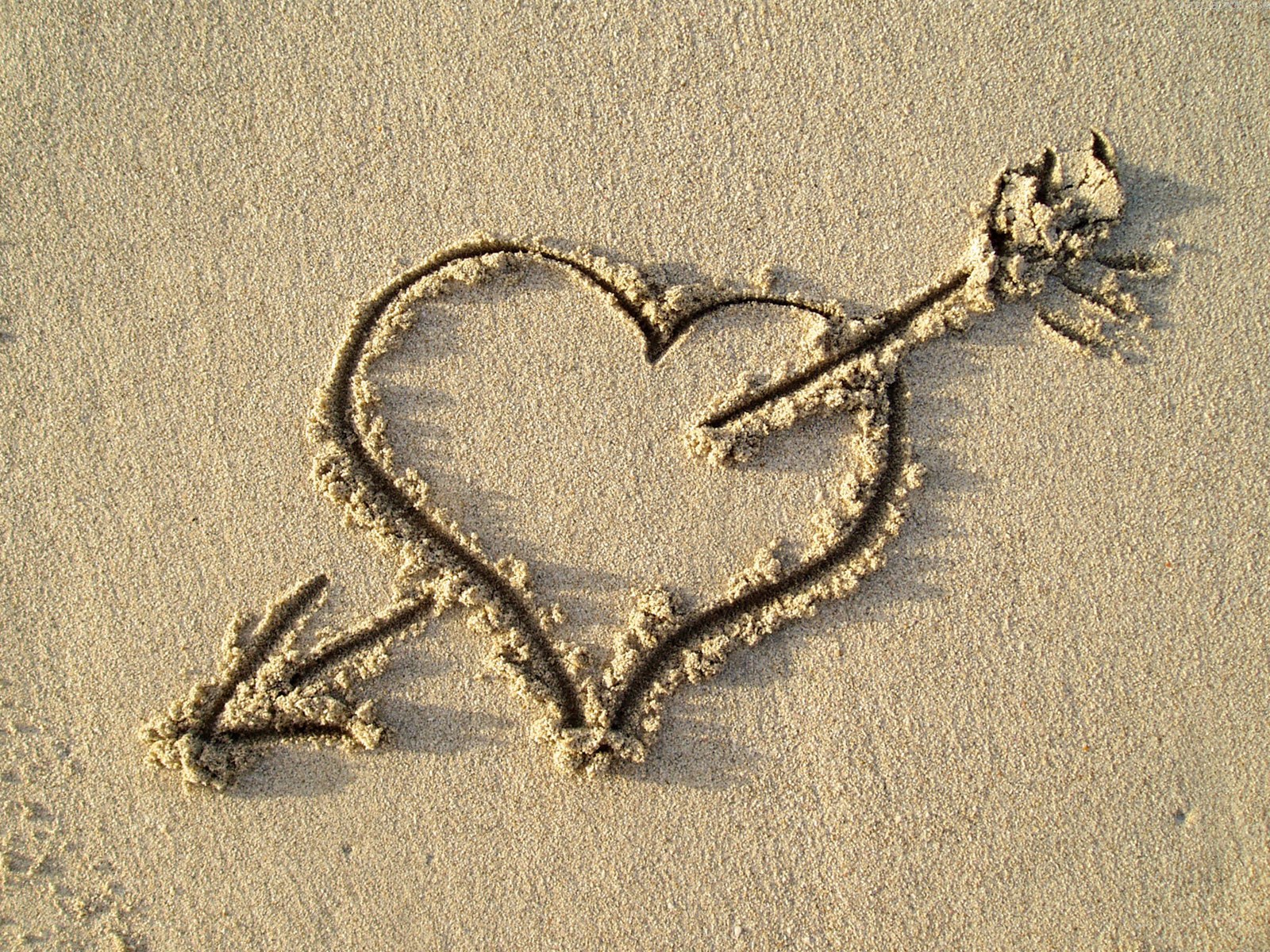 heart and arrow drawn in sand