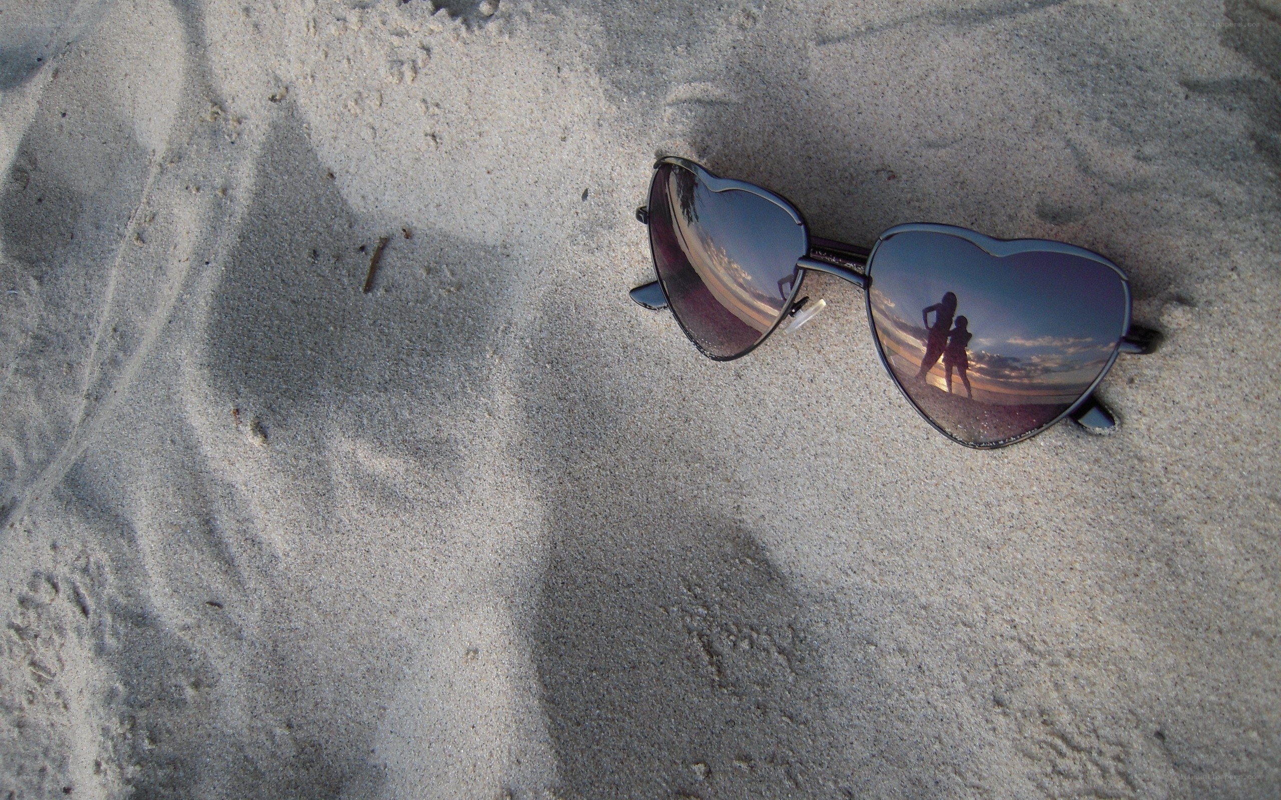 Heart-shaped sunglasses on sand