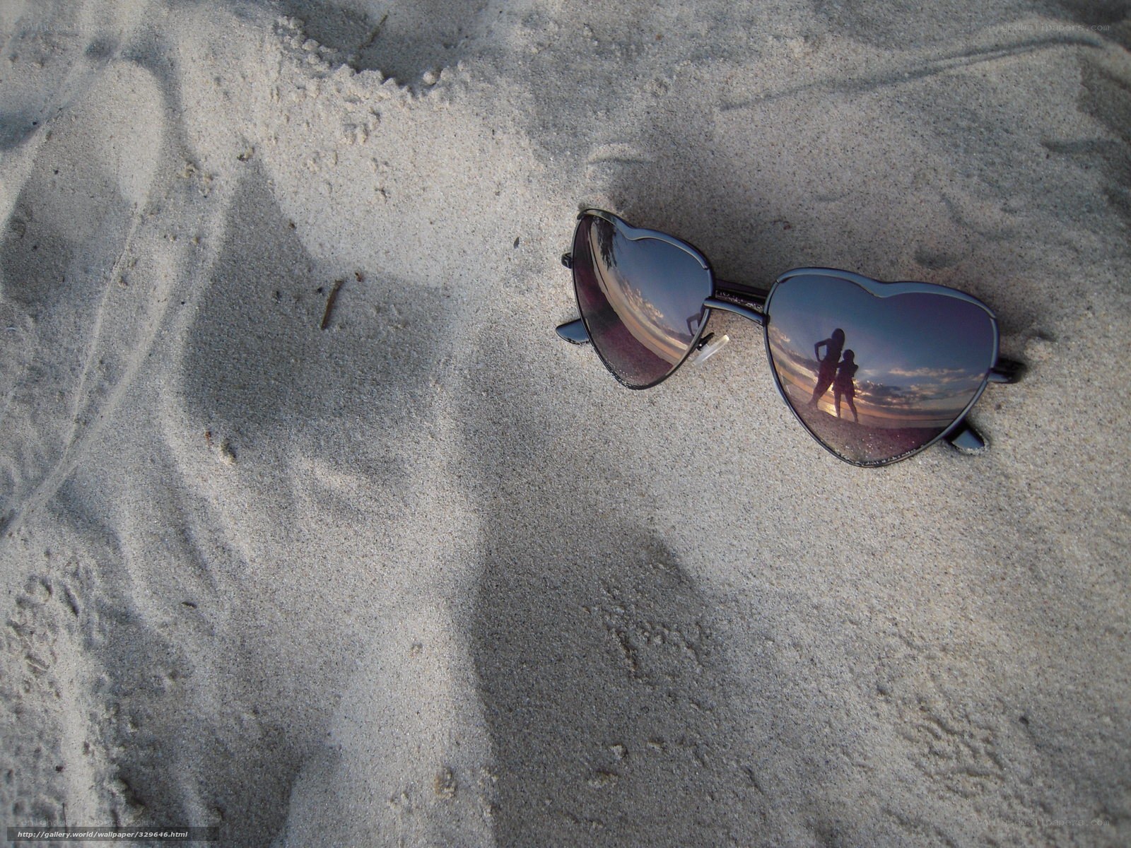 Heart-shaped sunglasses on sand