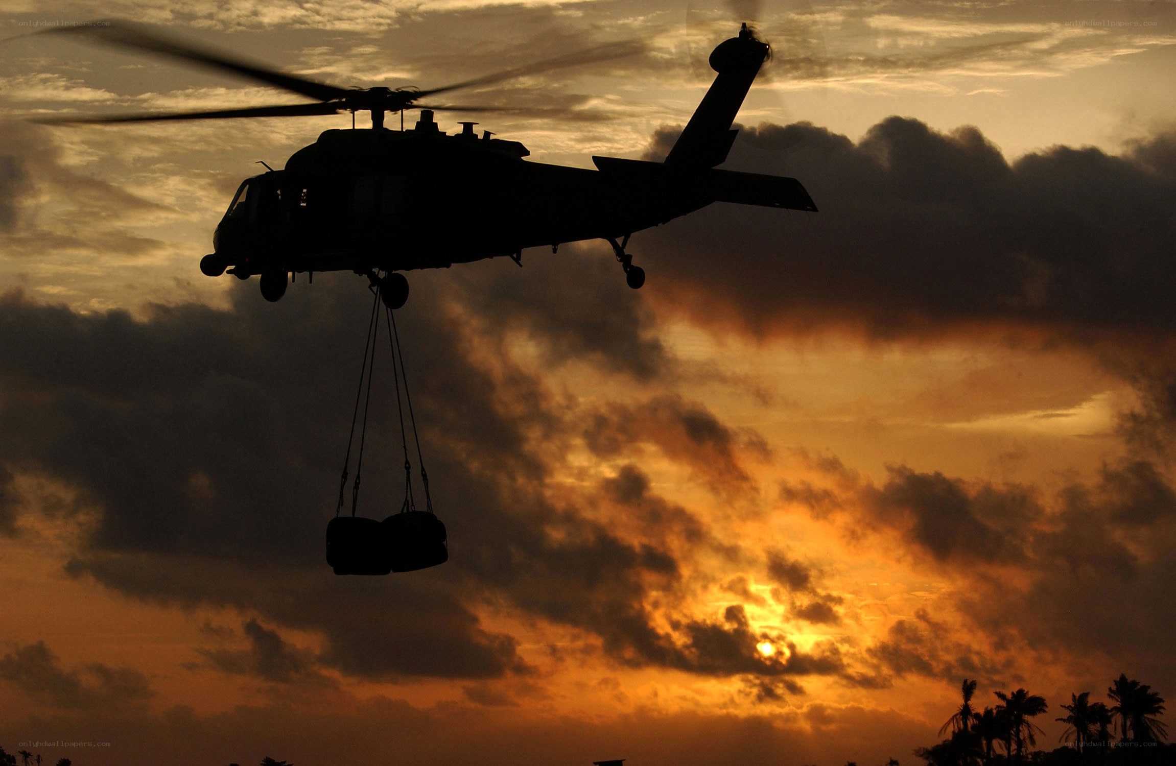 Helicopter at sunset carrying cargo