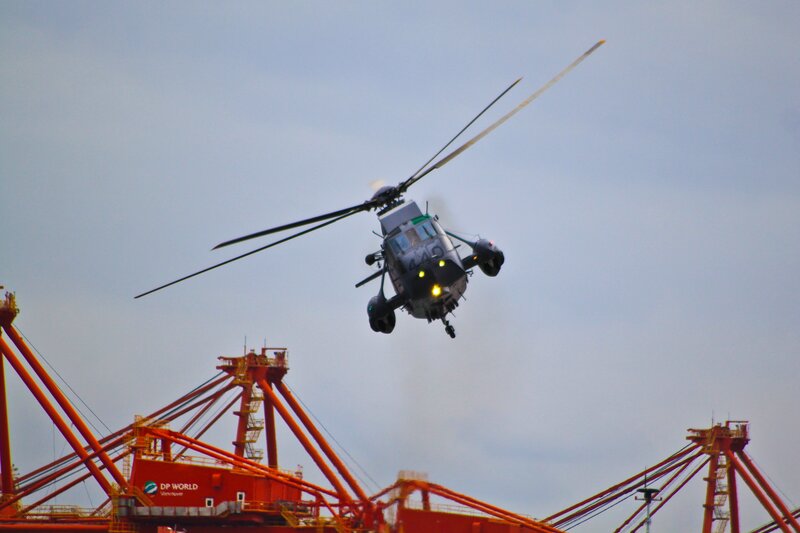 Helicopter flying over port cranes