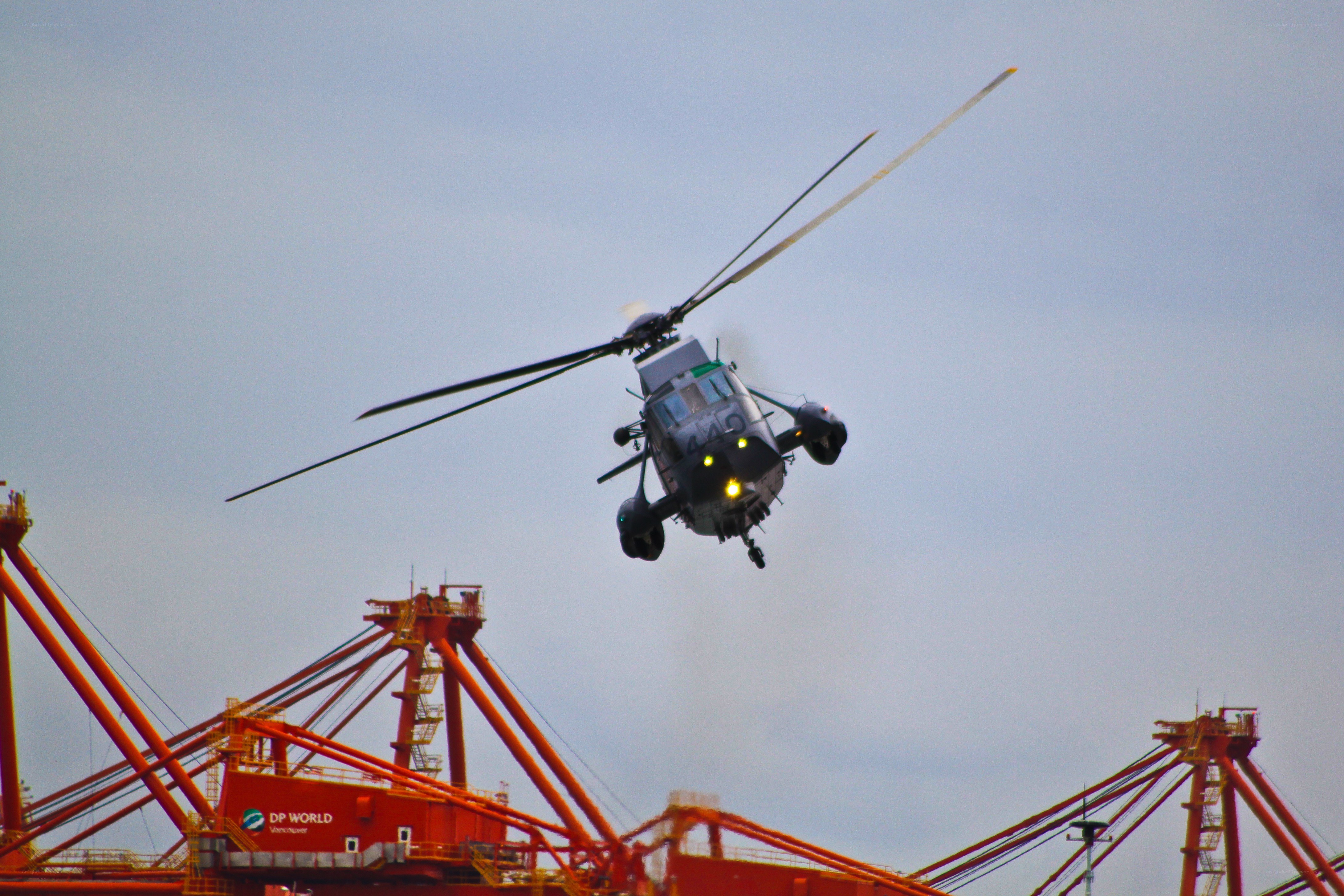 Helicopter flying over port cranes