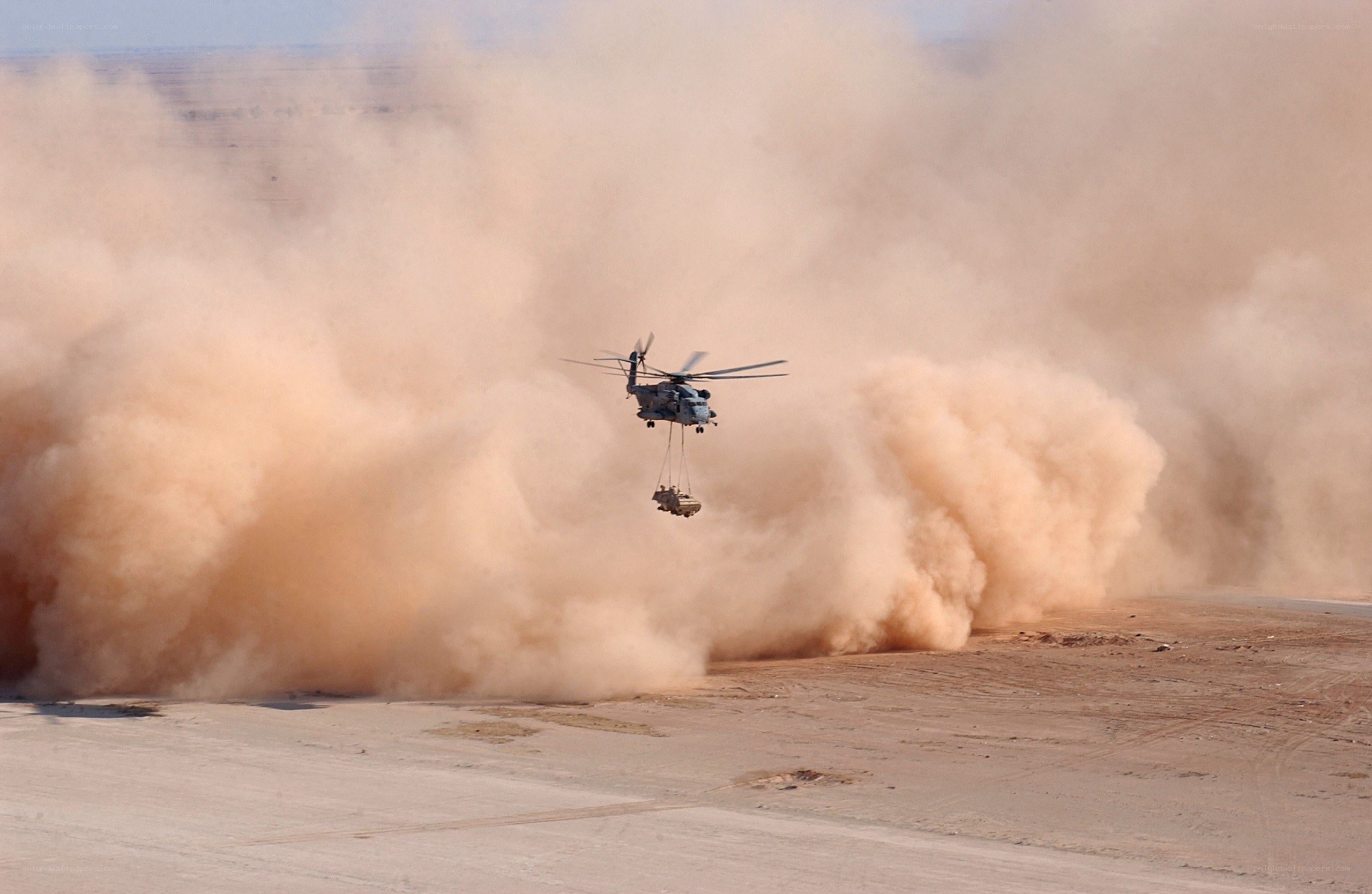 Helicopter lifting vehicle in desert