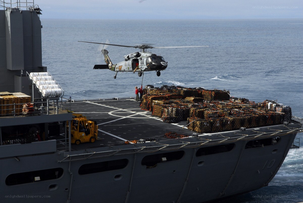 Helicopter lifts cargo on ship deck