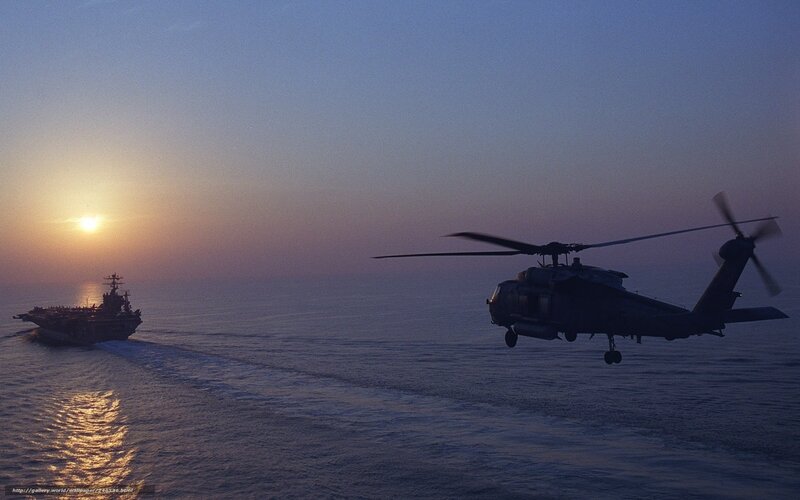 Helicopter near aircraft carrier at sunset