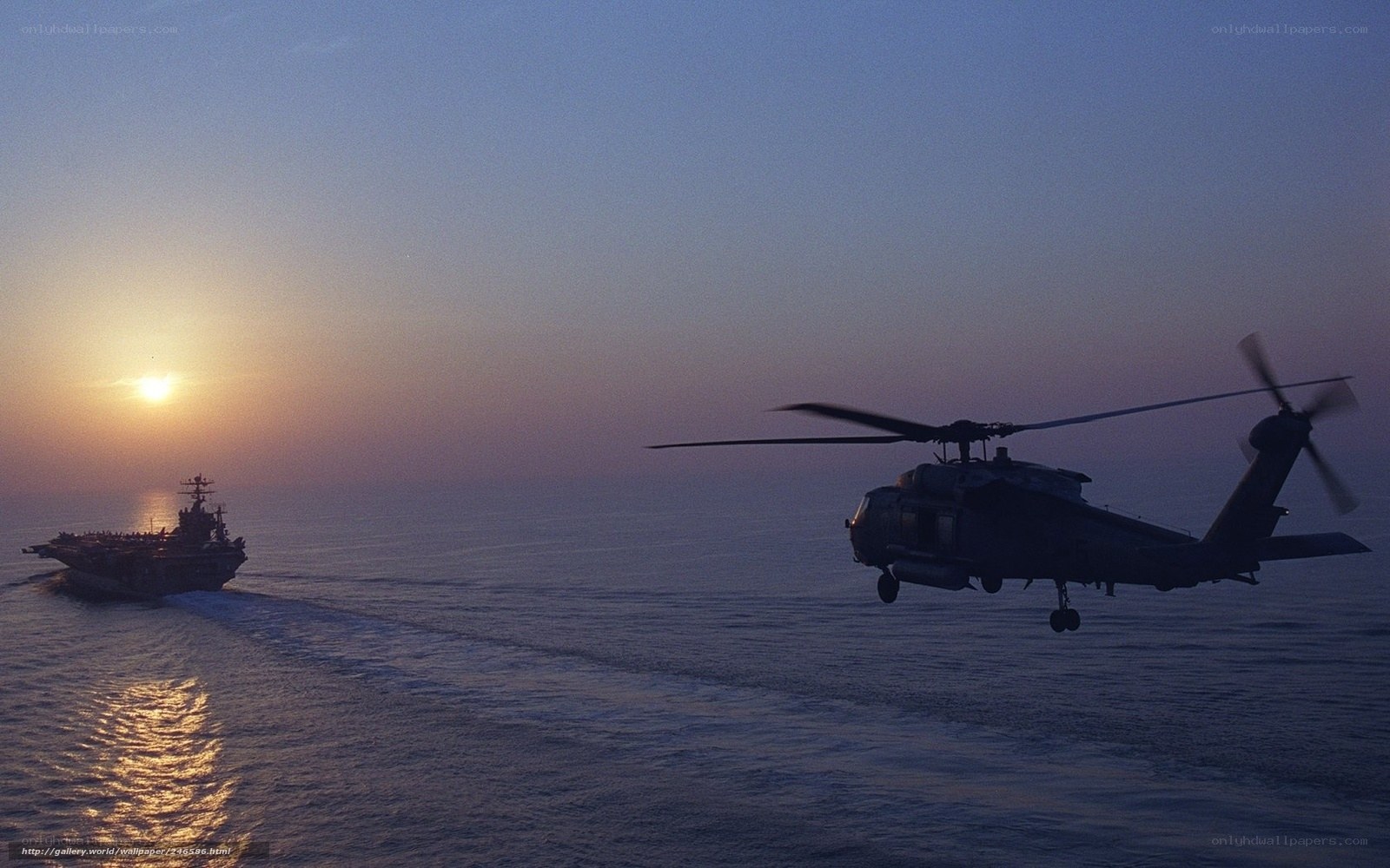 Helicopter near aircraft carrier at sunset