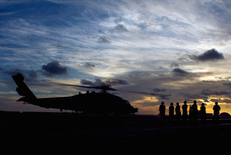 Helicopter on aircraft carrier at sunset