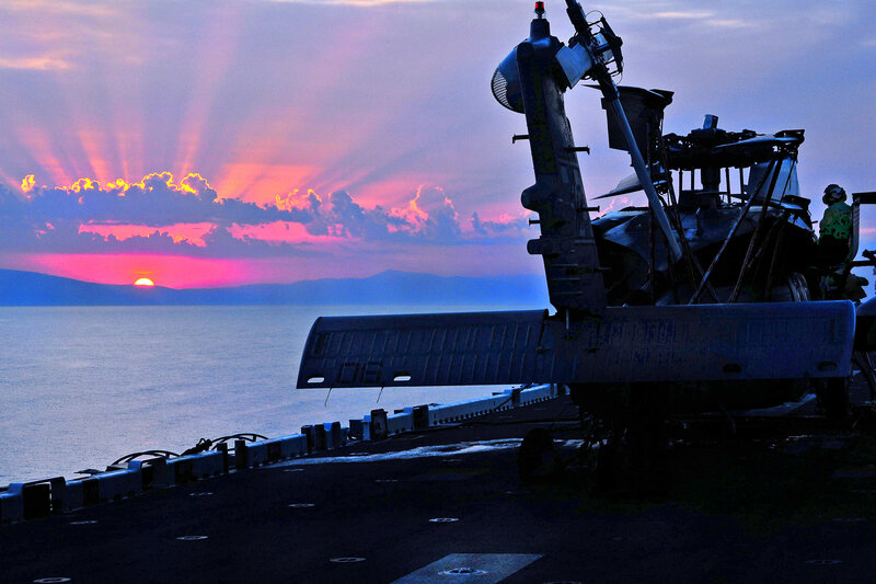 Helicopter on aircraft carrier at sunset