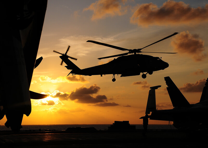 Helicopter on aircraft carrier at sunset