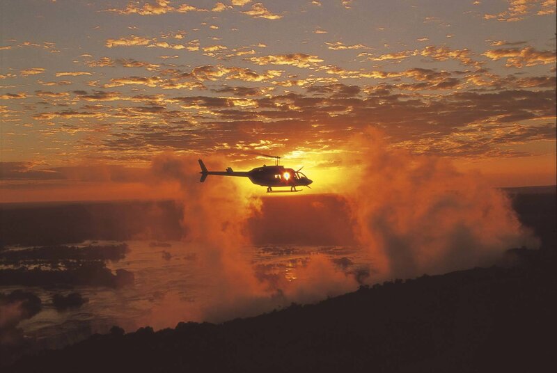 Helicopter over a waterfall at sunset