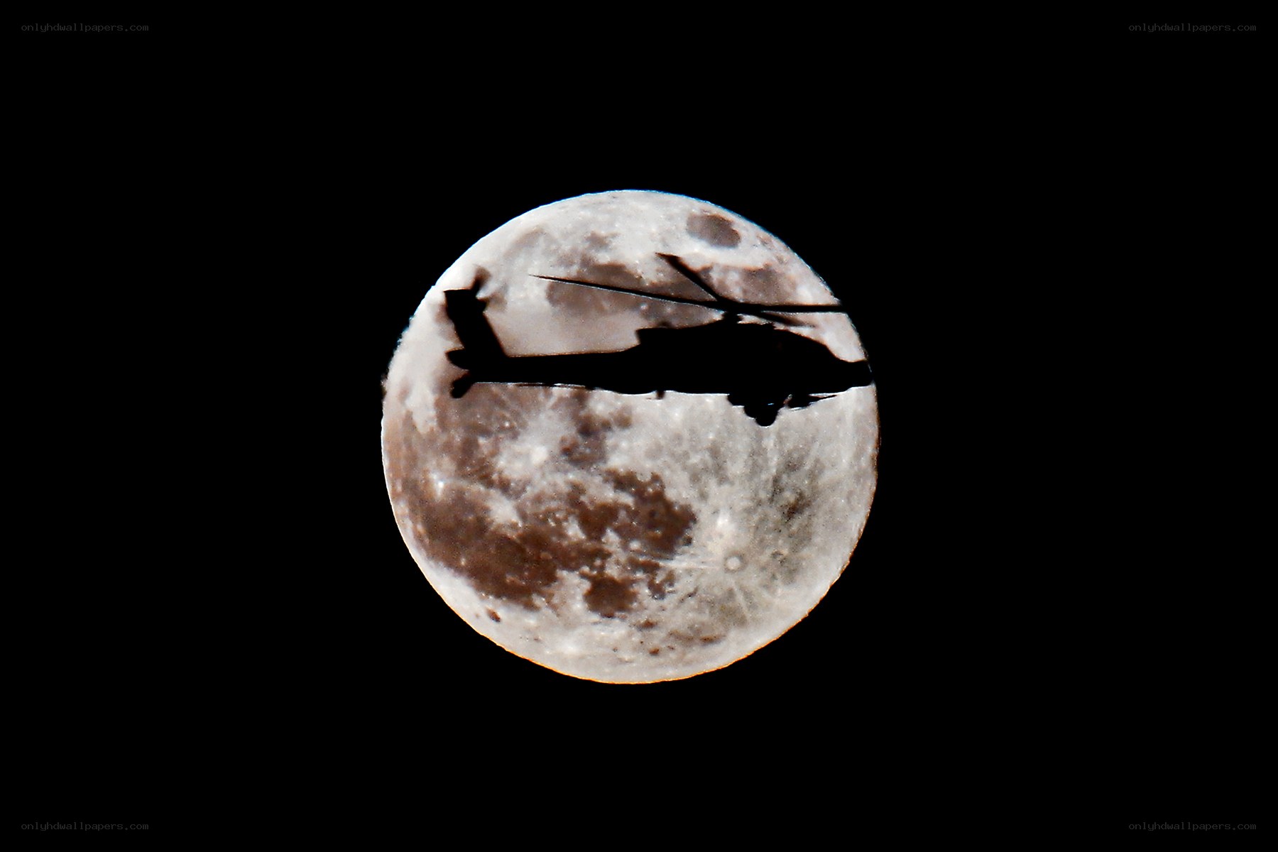 Helicopter silhouetted against the moon