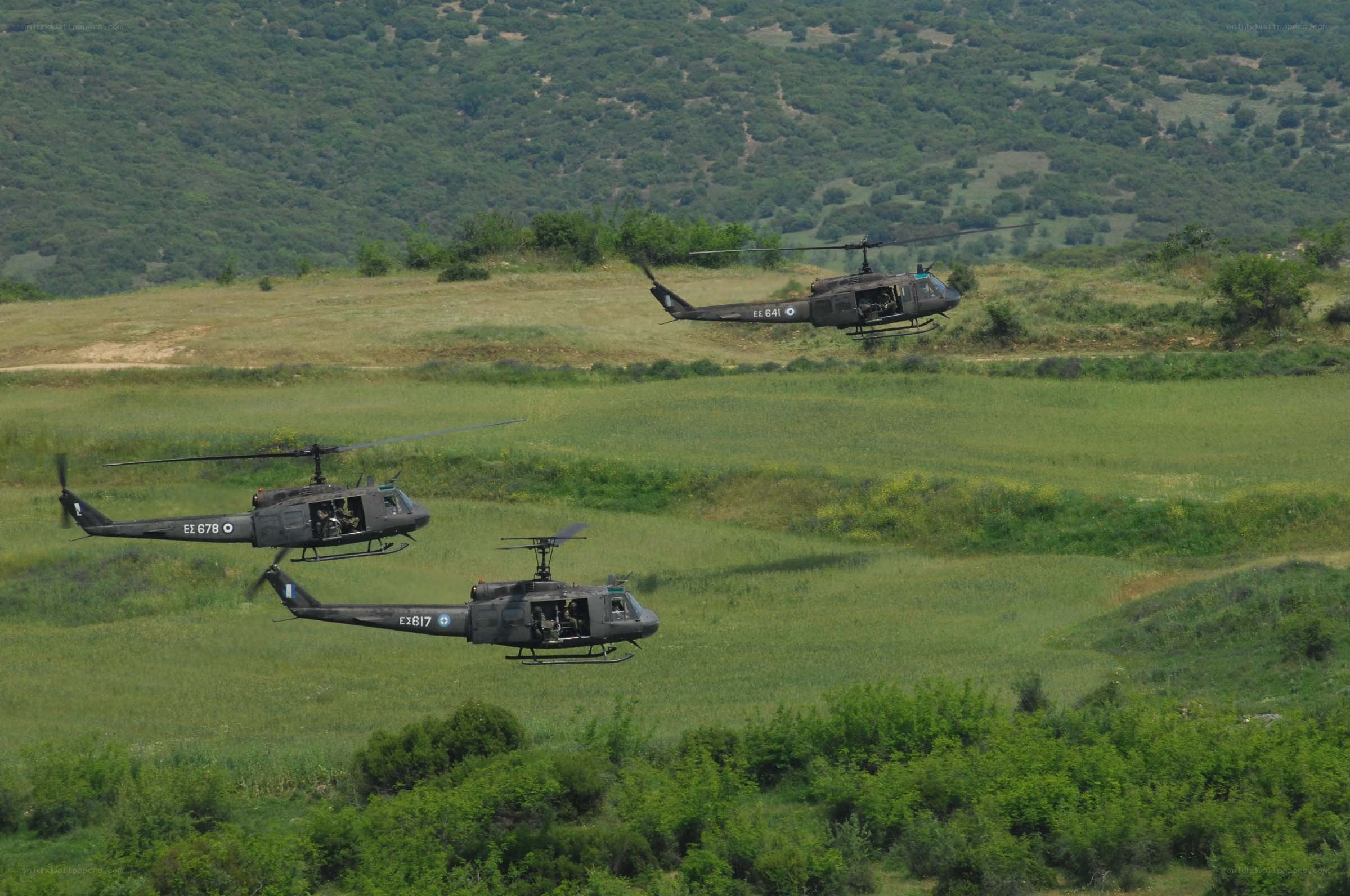 Helicopters flying over green fields