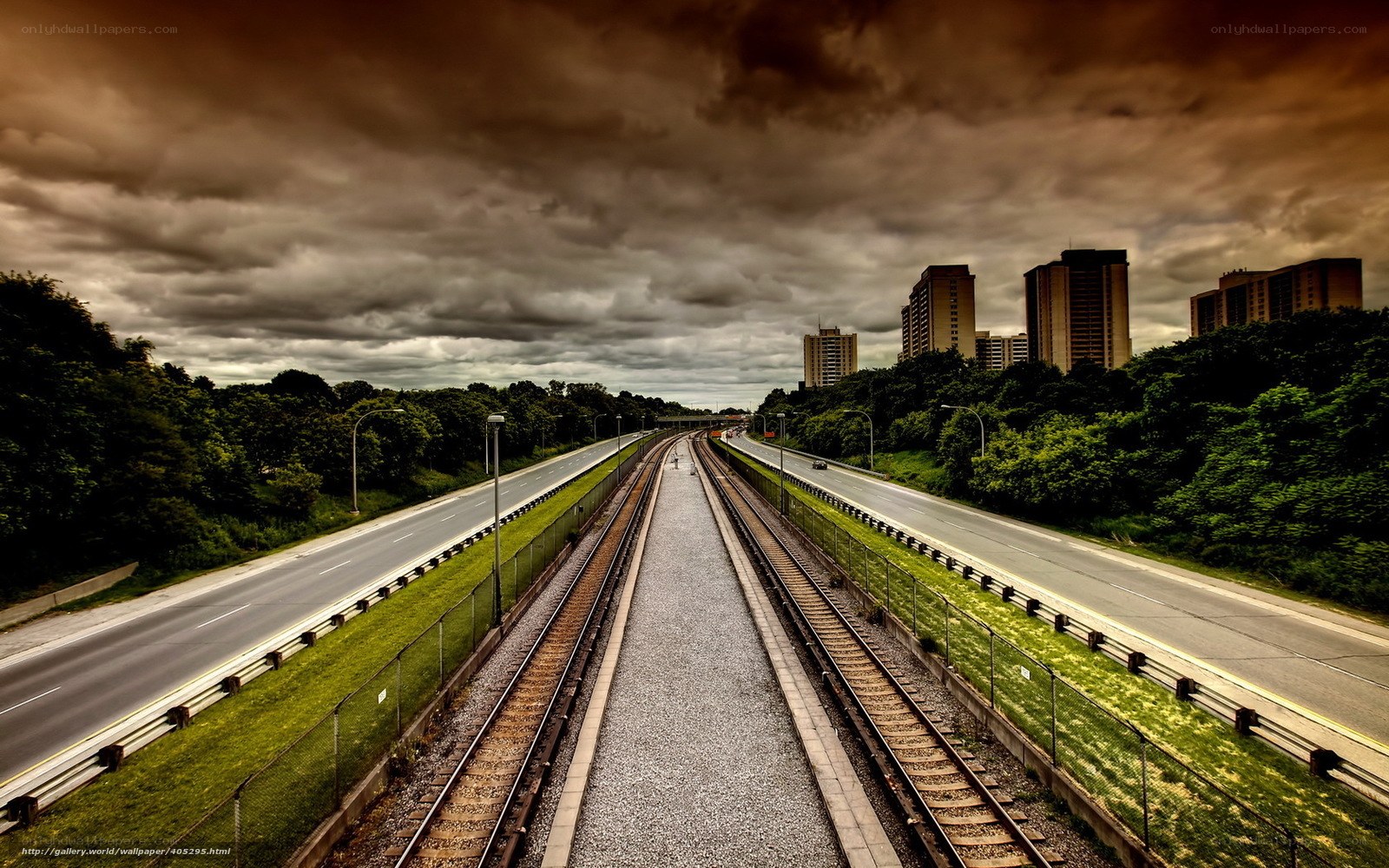 Highway and train tracks under stormy sky