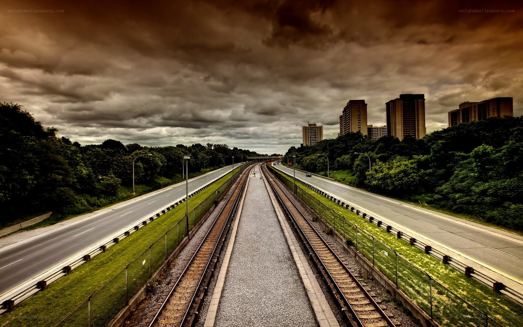 Highway and train tracks under stormy sky