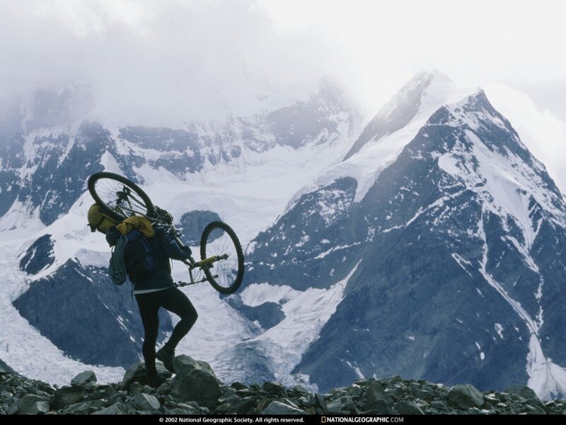 Hiker carrying bike in mountains