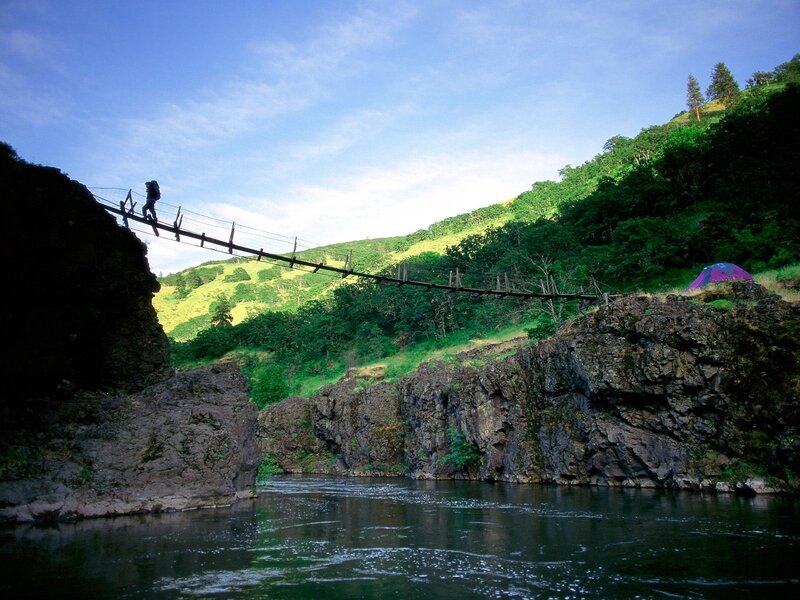 Hiker crossing river bridge