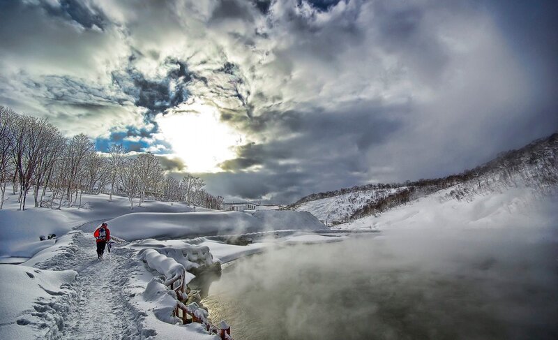 Hiker near steaming river in winter
