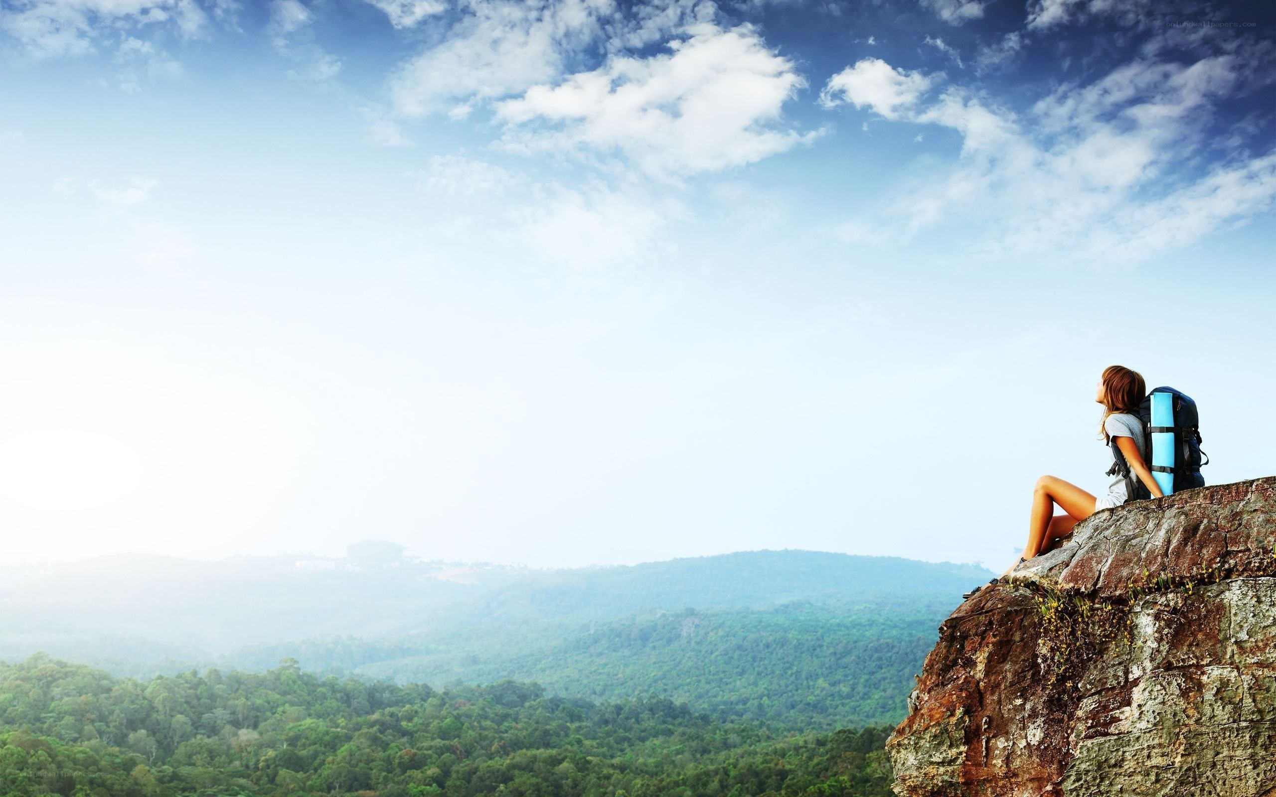 Hiker on a cliff overlooking a forest