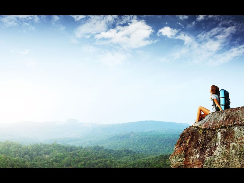 Hiker on a cliff overlooking forest