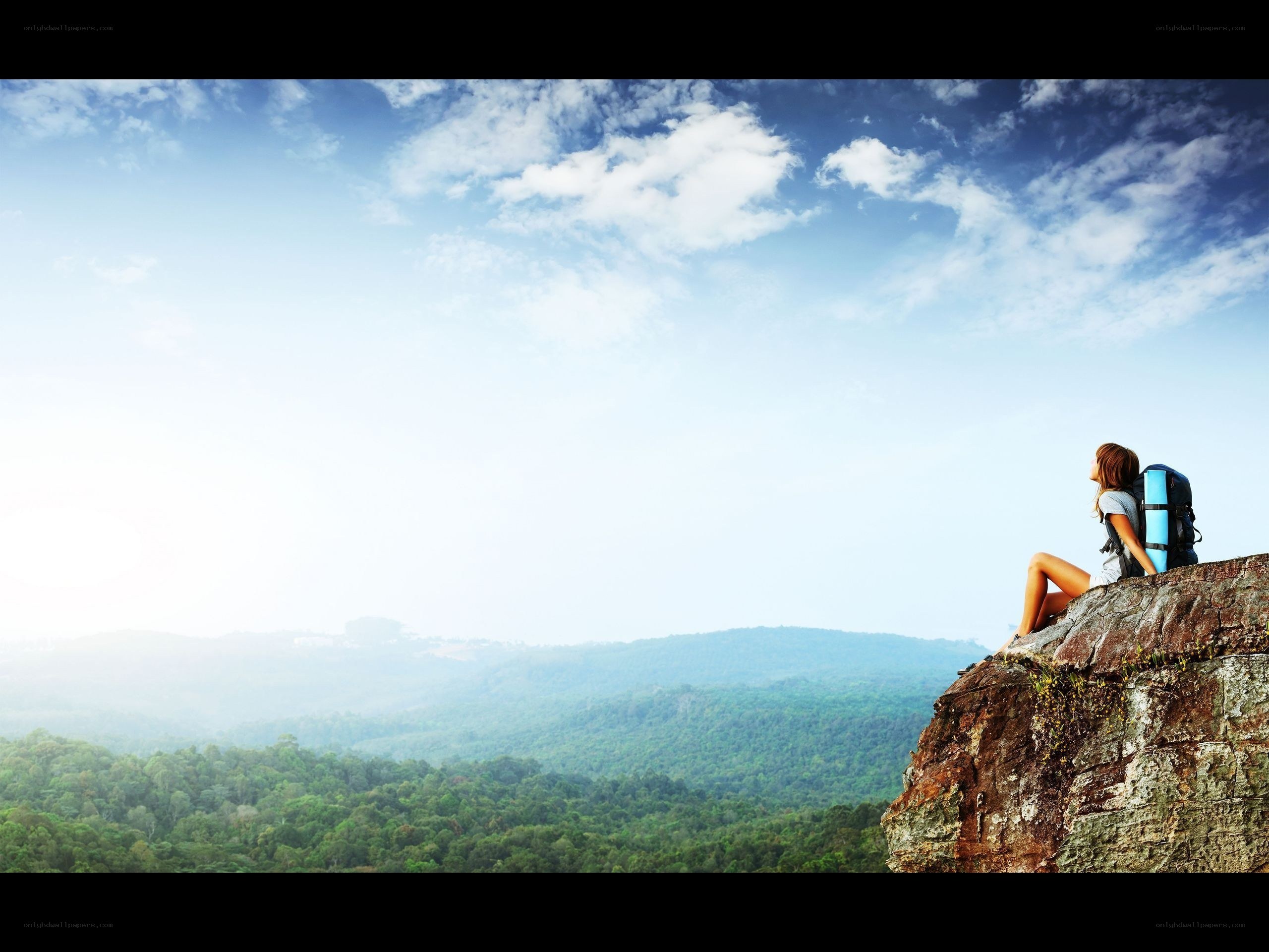 Hiker on a cliff overlooking forest
