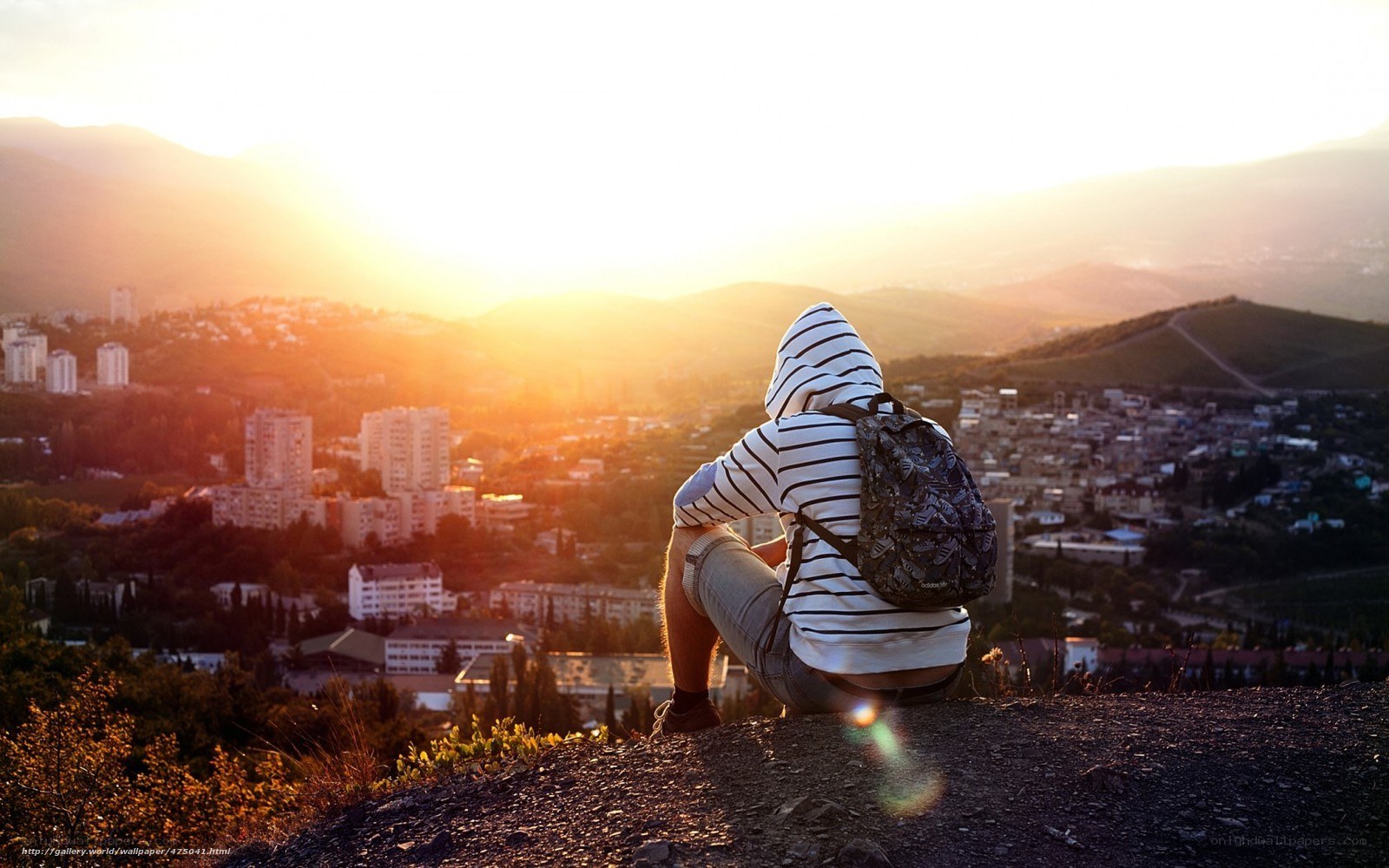 Hiker overlooking city at sunset