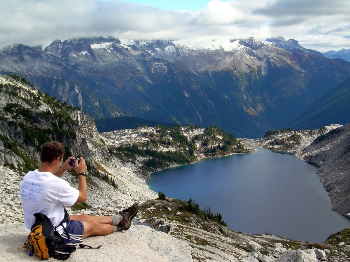 Hiker photographing mountain lake