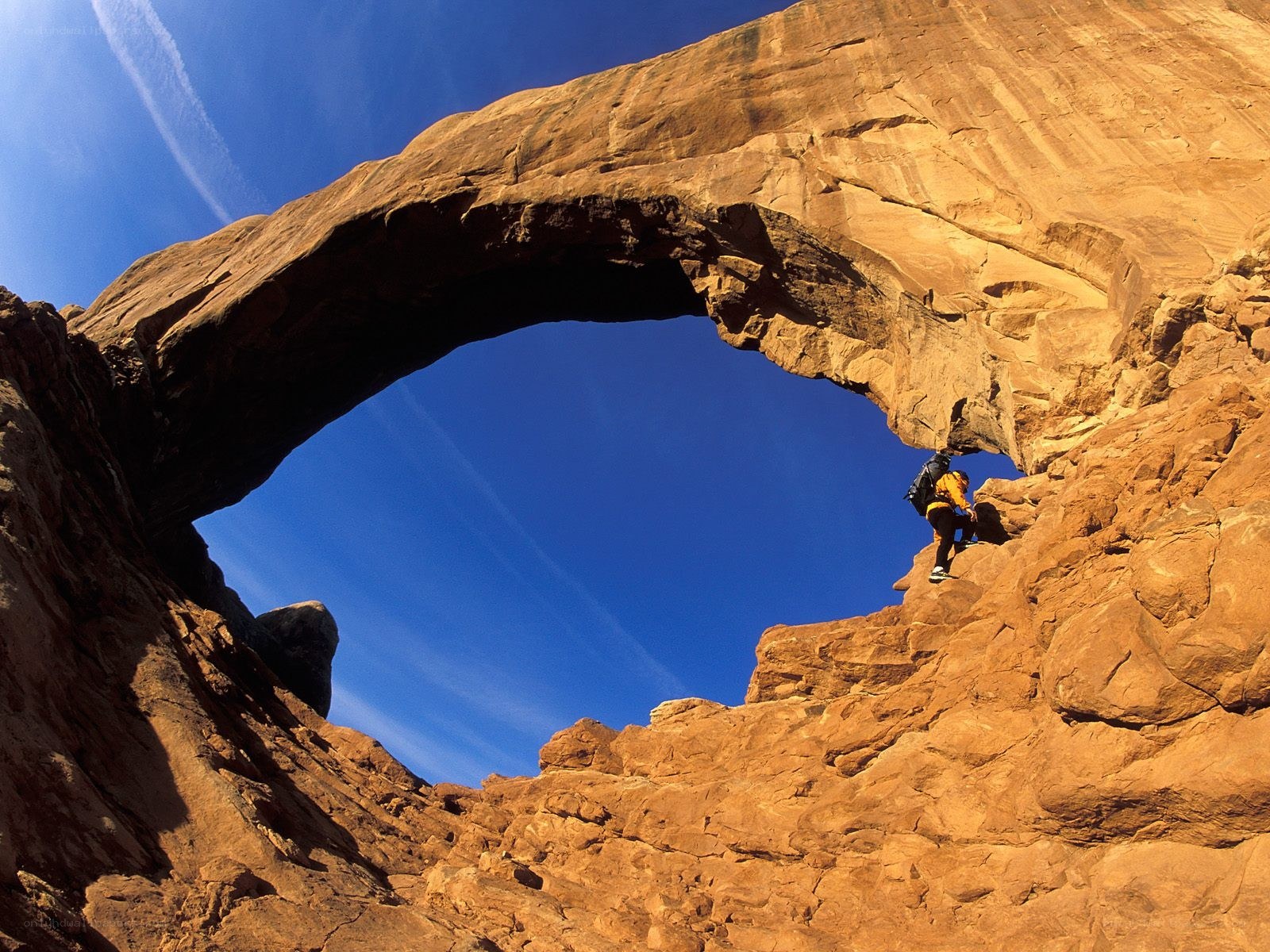 hiker under a natural arch