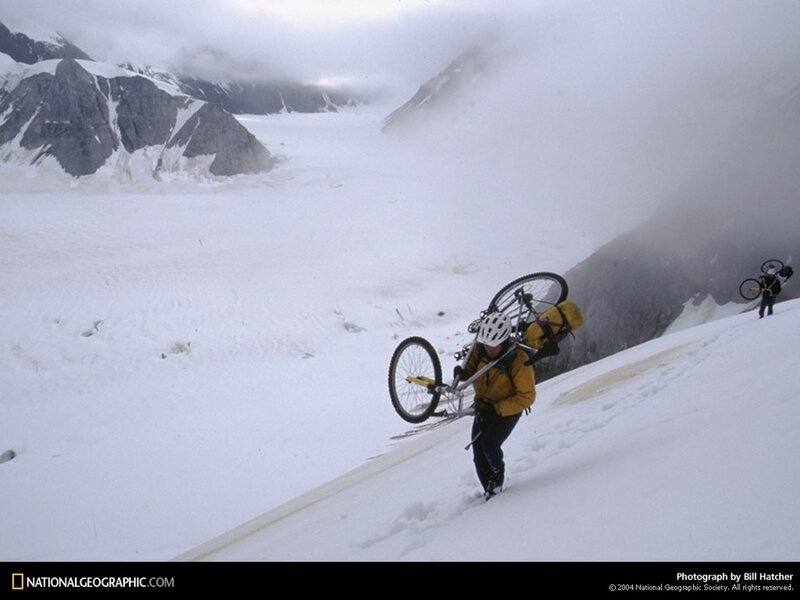 Hikers carrying bikes on a glacier