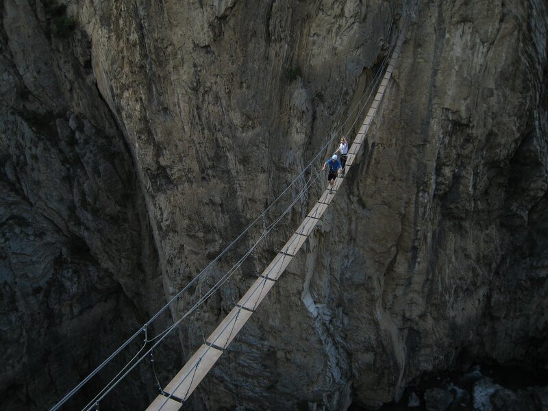 Hikers on a cliffside suspension bridge