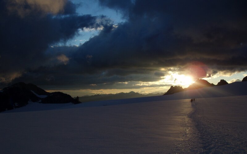 Hikers on a snowy mountain at sunset