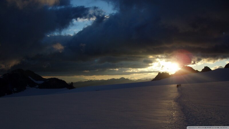 Hikers on a snowy mountain at sunset