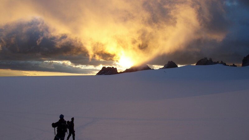 Hikers on a snowy mountain at sunset