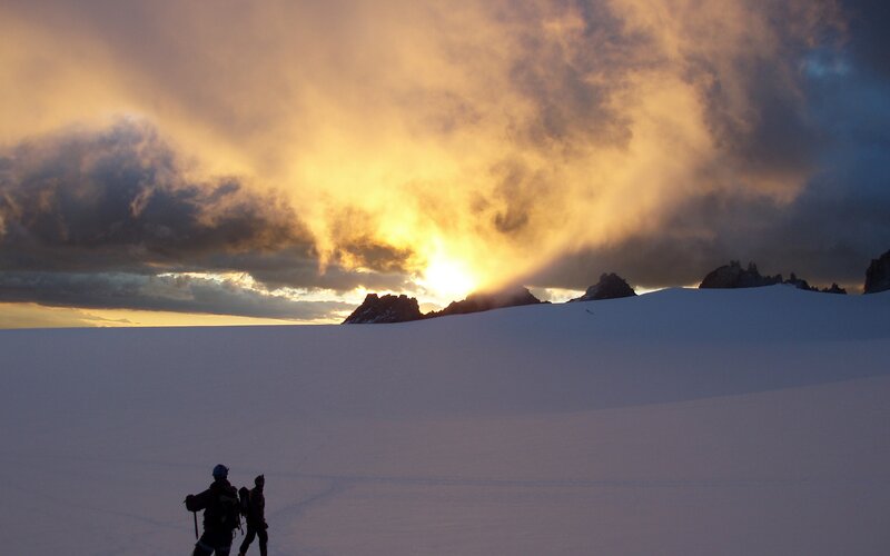 Hikers on a snowy mountain at sunset
