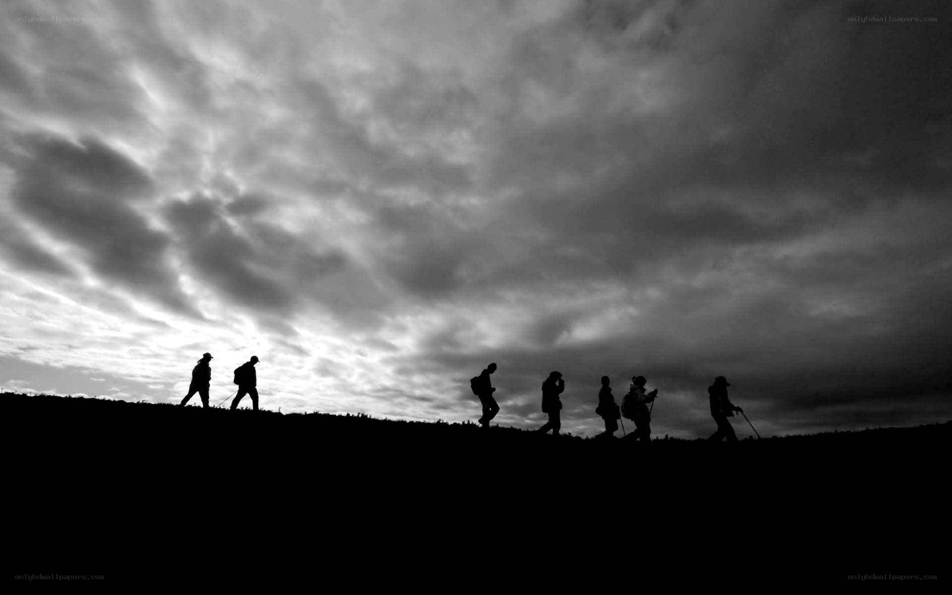 hikers silhouetted against cloudy sky