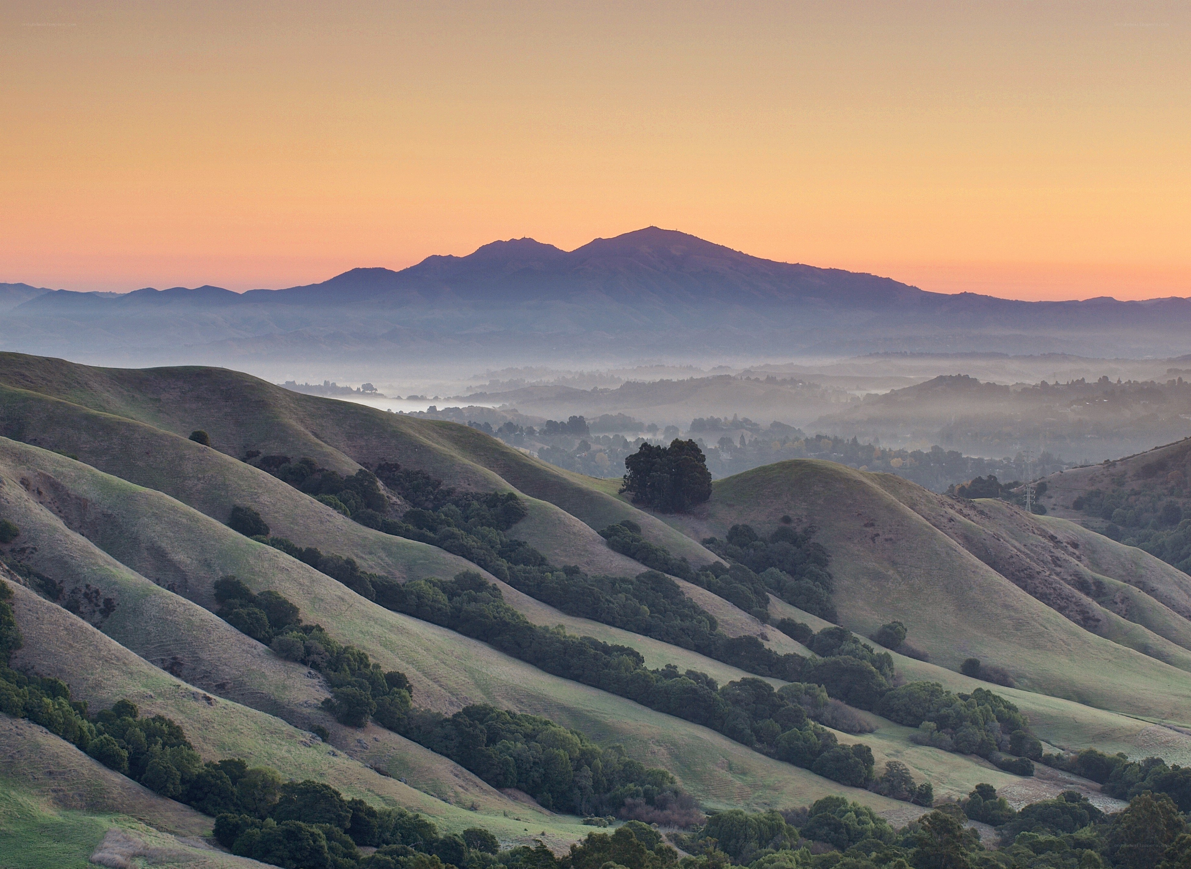 Hills at sunrise with distant mountains