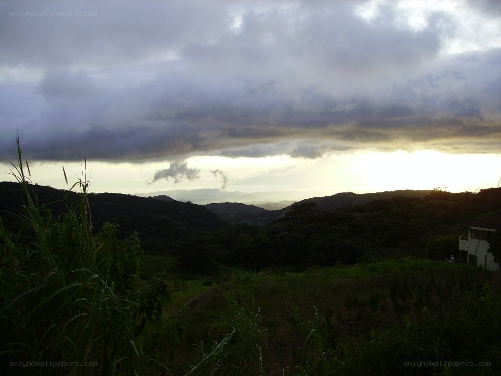 Hills under cloudy sky at sunset