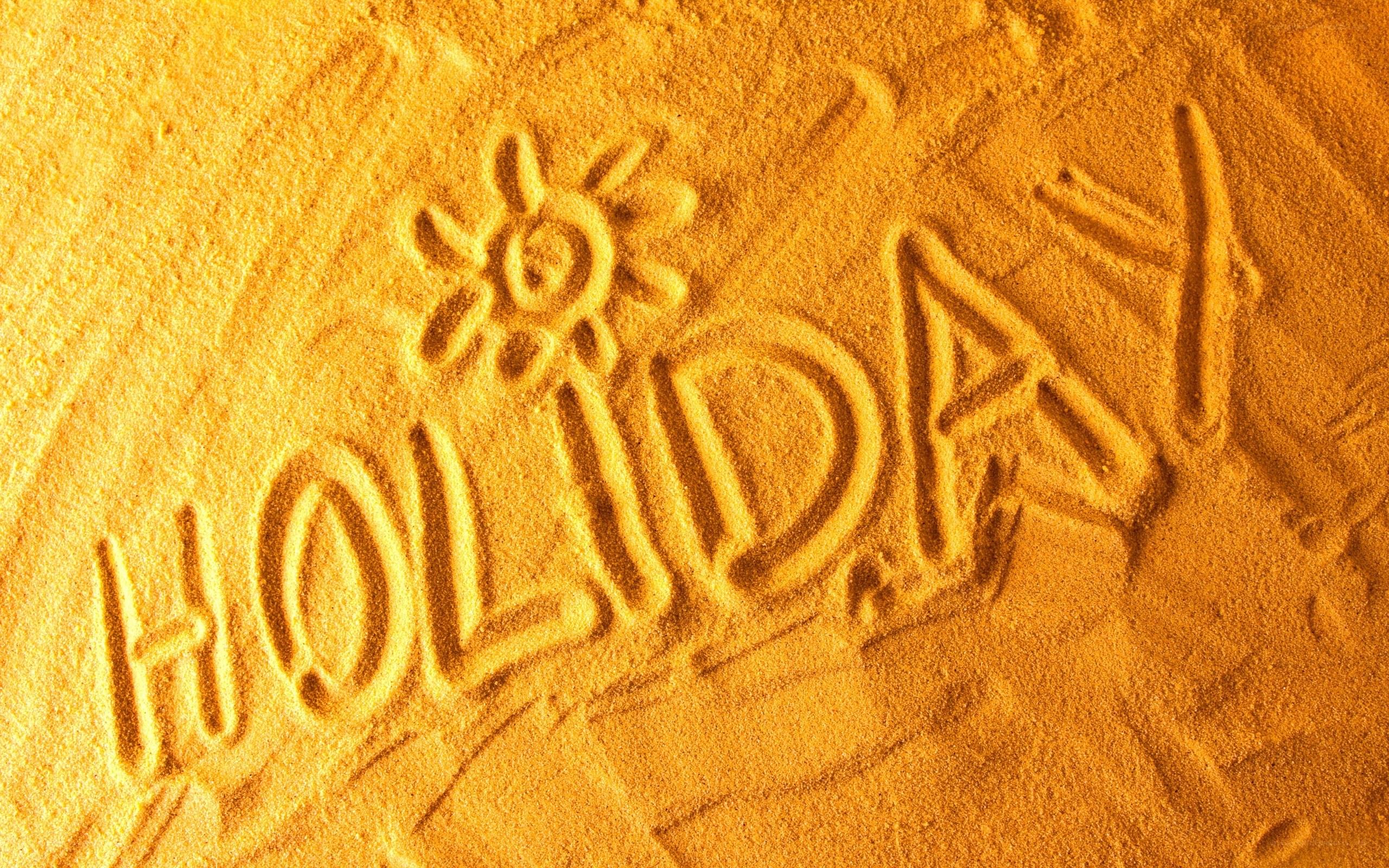 holiday written in sand