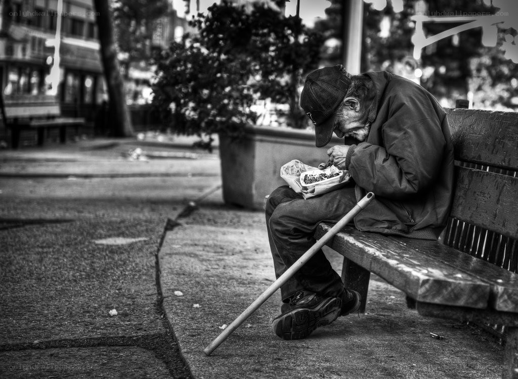 Homeless man eating on bench