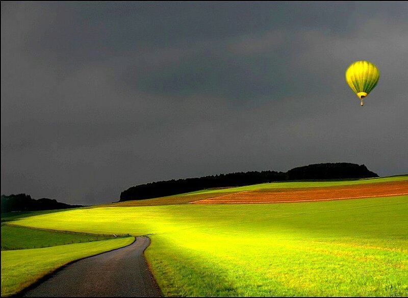 Hot air balloon over green fields