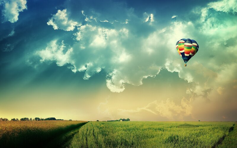 Hot air balloon over green fields