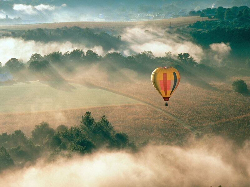 Hot air balloon over misty fields