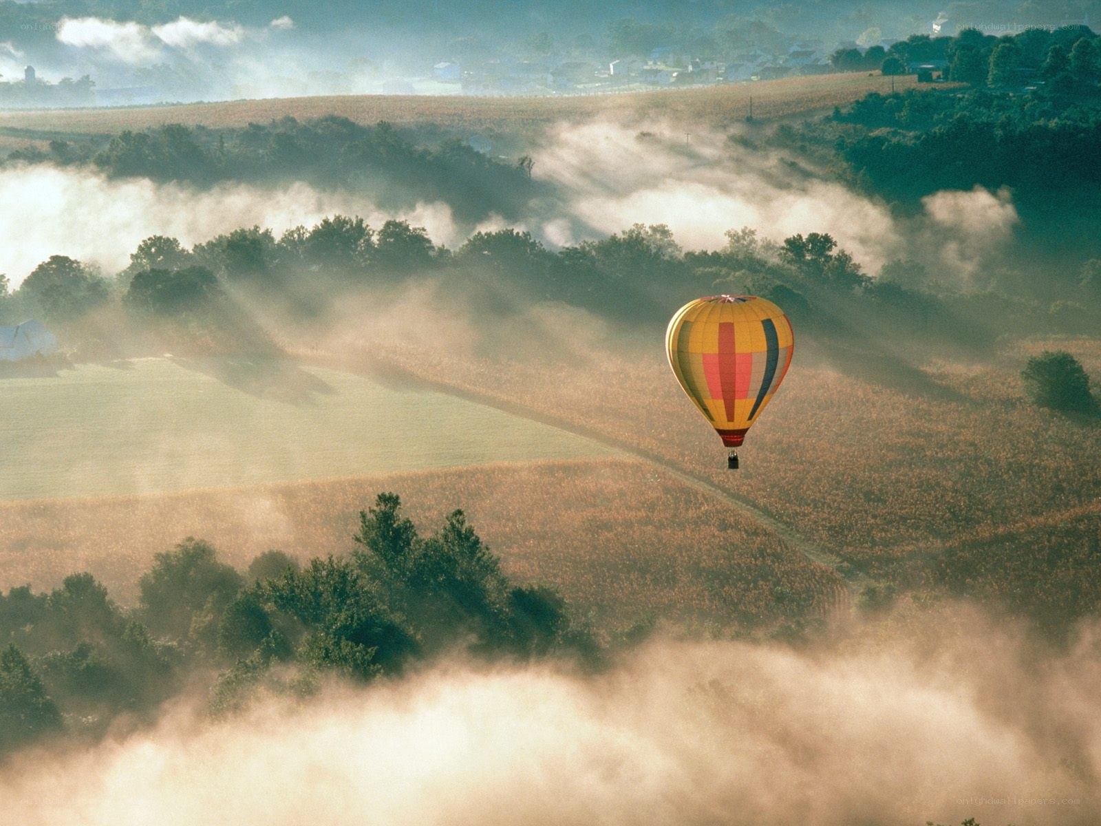 Hot air balloon over misty fields