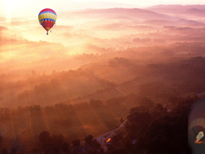 Hot air balloon over misty hills